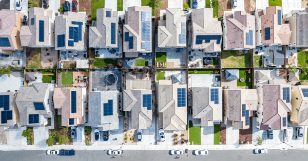 Neighborhood with solar panels on roofs and cars parked outside